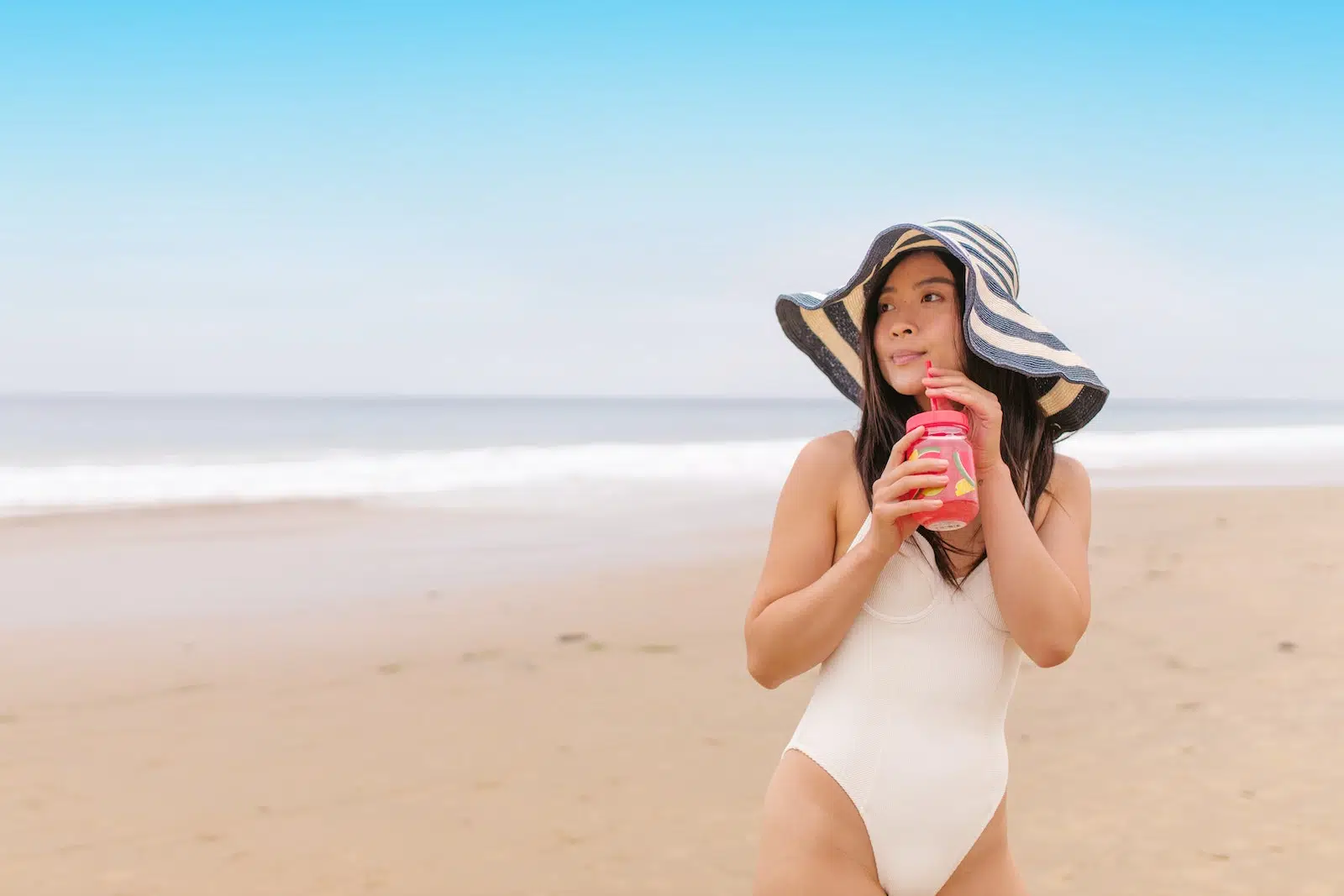 A Woman in a Maillot Drinking a Beverage at the Beach