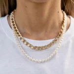 Collier à grosse maille doré et rang de perles sur un t-shirt blanc