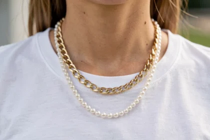 Collier à grosse maille doré et rang de perles sur un t-shirt blanc